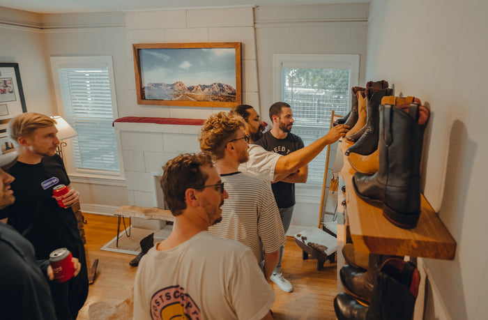 Guests pull boots off the wall to try on during a group fitting at Chisos HQ