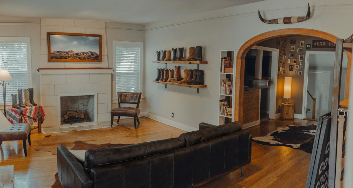 The main room at Chisos HQ with a leather sofa, fireplace, boot shelves and an arched doorway