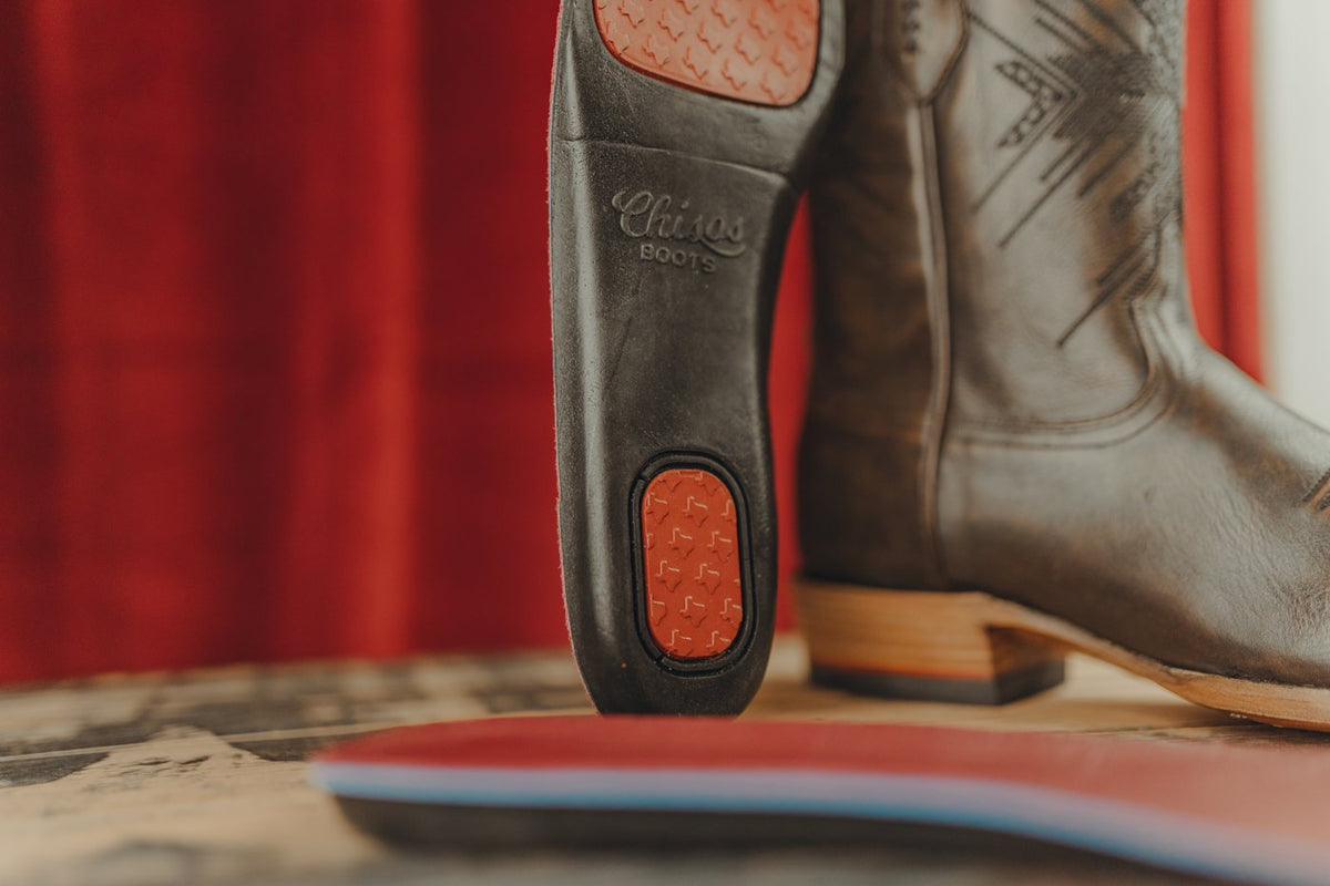 The removable Chisos comfort insole stands beside a brown boot, with its heel and forefoot gel pads visible.
