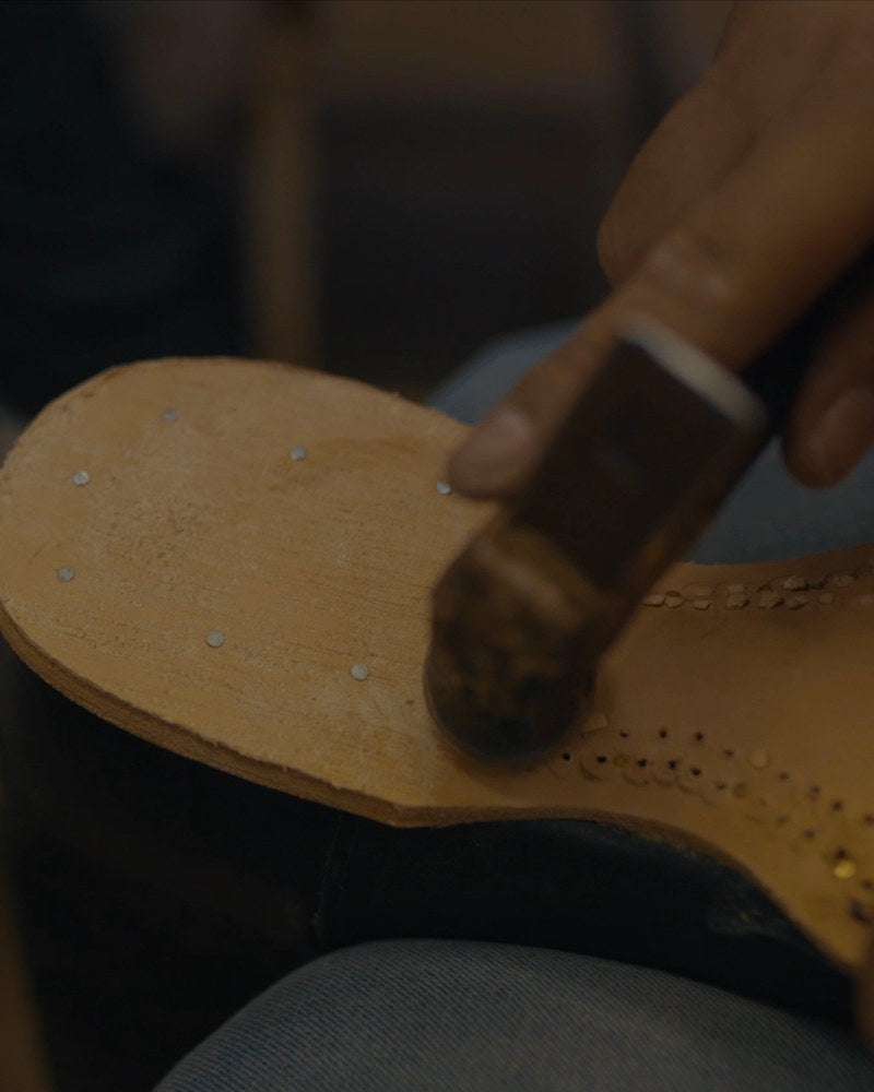 A bootmaker hammering the leather sole by hand